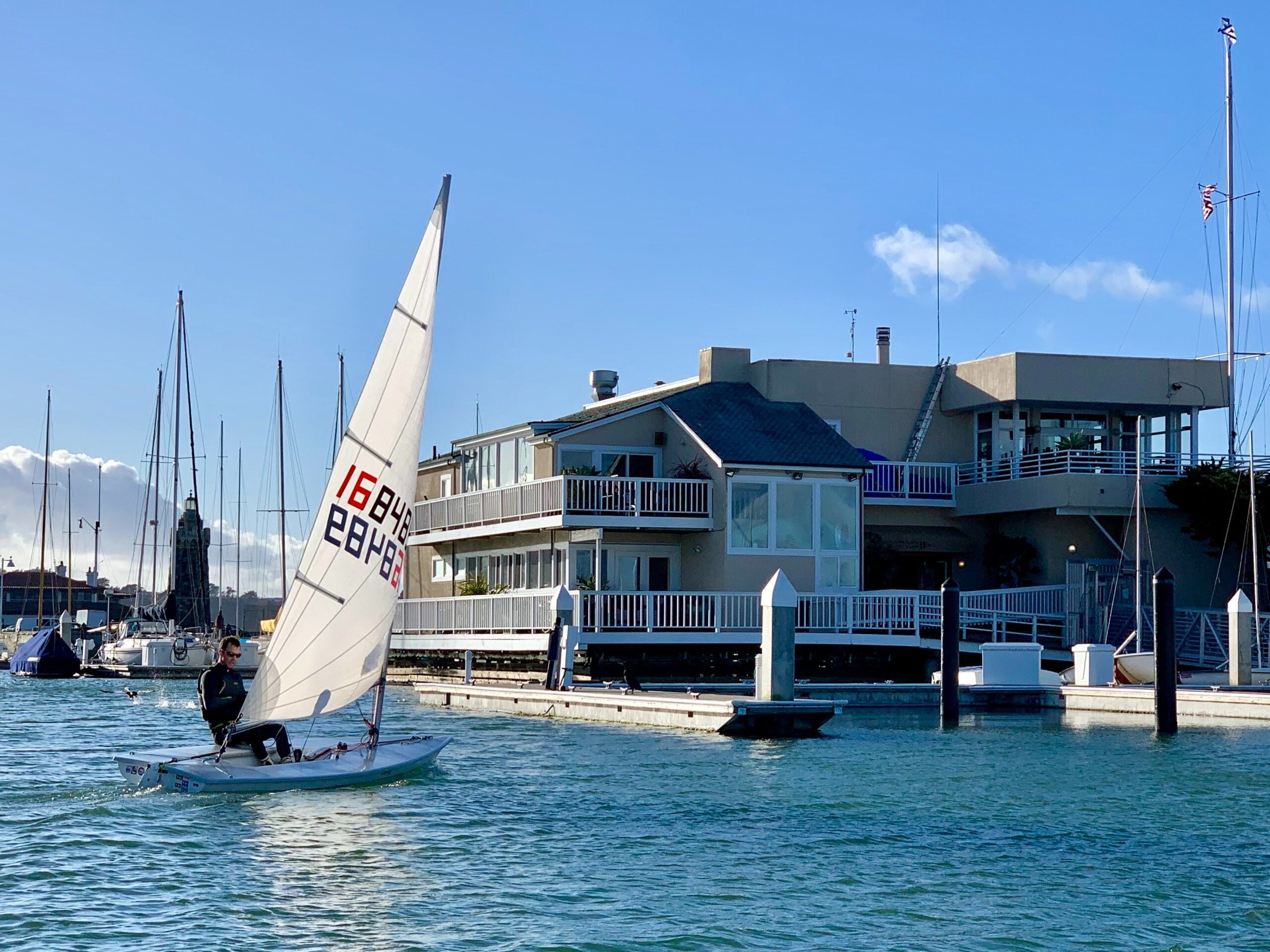 Sailboat on San Francisco Bay beside a waterfront yacht club